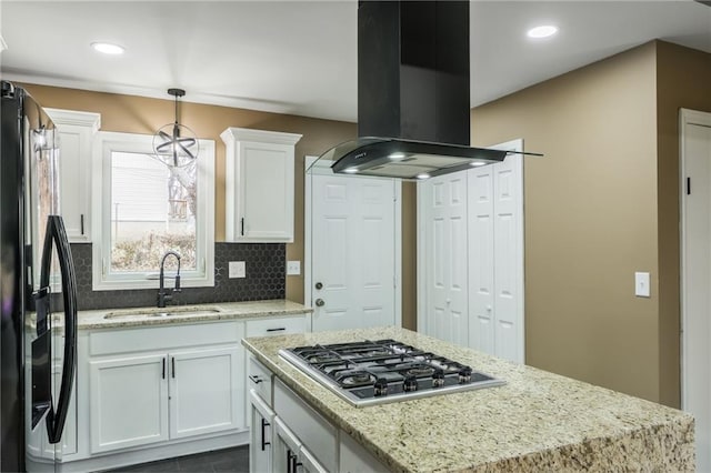 kitchen featuring sink, hanging light fixtures, island exhaust hood, stainless steel gas cooktop, and black fridge