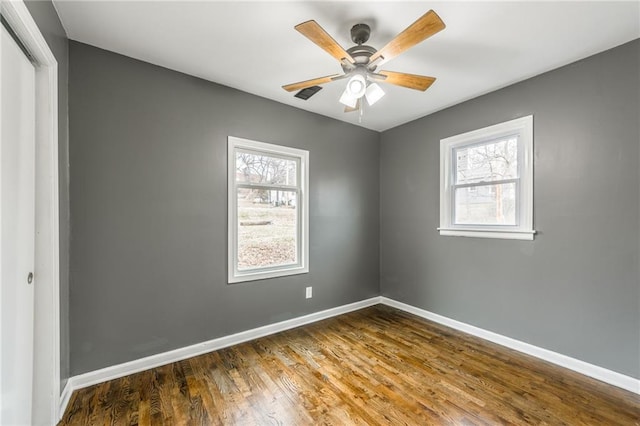 empty room with dark hardwood / wood-style flooring, ceiling fan, and a healthy amount of sunlight