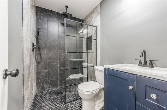 bathroom with vanity, tiled shower, and toilet