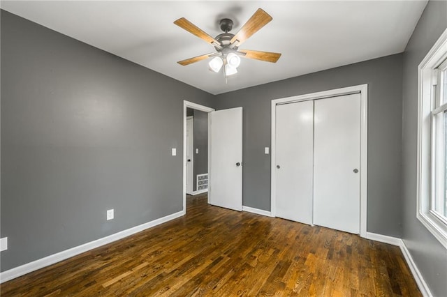 unfurnished bedroom with dark wood-type flooring, ceiling fan, and a closet