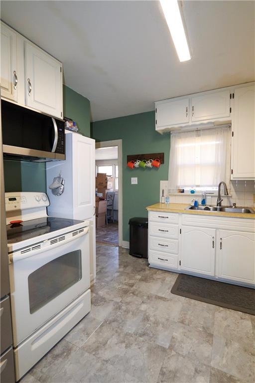 kitchen featuring tasteful backsplash, white cabinetry, sink, and white range with electric stovetop