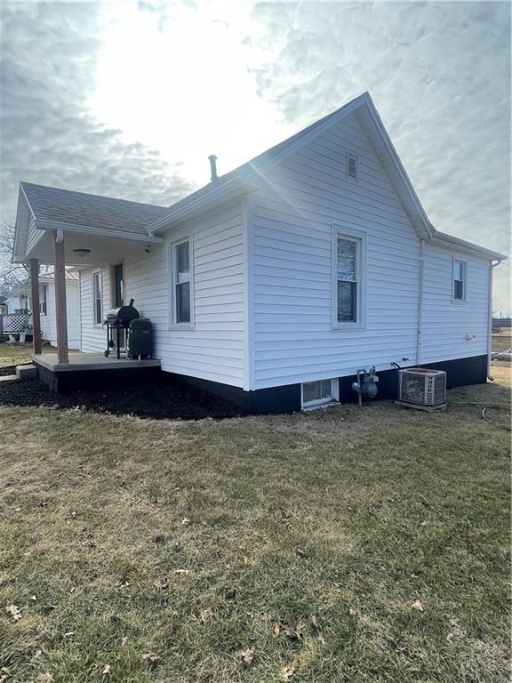 view of side of home with central AC, a yard, and covered porch