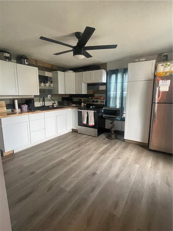 kitchen featuring white cabinetry, light wood-type flooring, ceiling fan, stainless steel appliances, and a textured ceiling