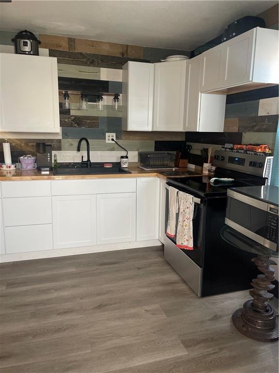 kitchen with dark wood-type flooring, appliances with stainless steel finishes, sink, and white cabinets