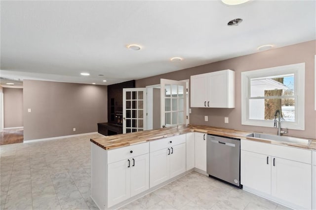 kitchen with sink, white cabinetry, wooden counters, stainless steel dishwasher, and kitchen peninsula