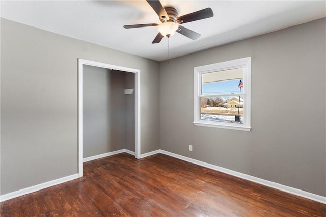 unfurnished bedroom featuring dark wood-type flooring, a closet, and ceiling fan