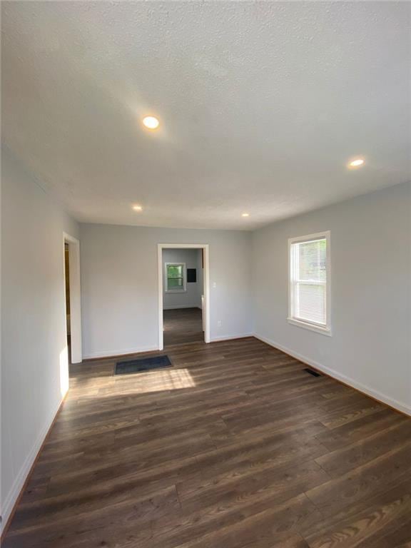 empty room with a textured ceiling and dark hardwood / wood-style flooring