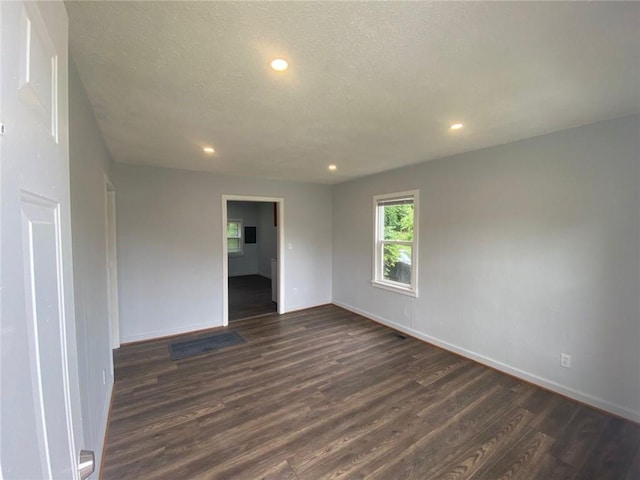 unfurnished room featuring dark hardwood / wood-style flooring and a textured ceiling