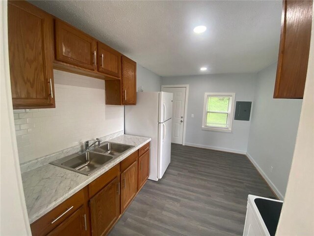 kitchen featuring sink, backsplash, white fridge, electric panel, and dark wood-type flooring