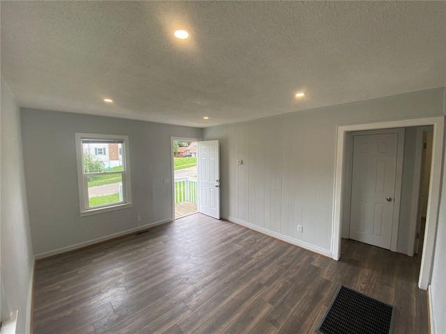 unfurnished room with dark wood-type flooring and a textured ceiling