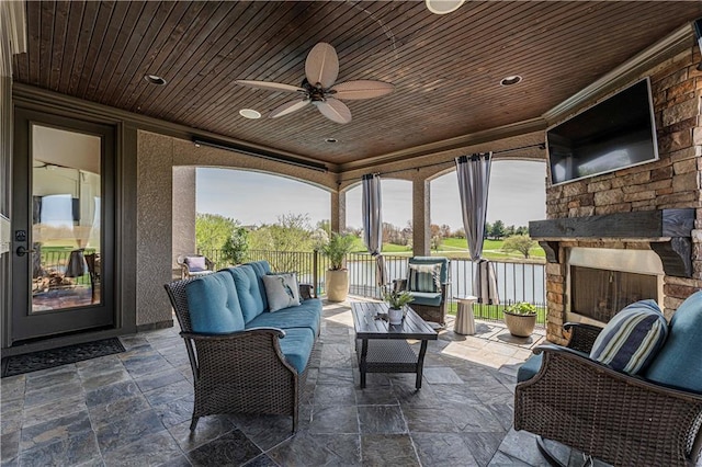 view of patio featuring a ceiling fan and an outdoor living space with a fireplace