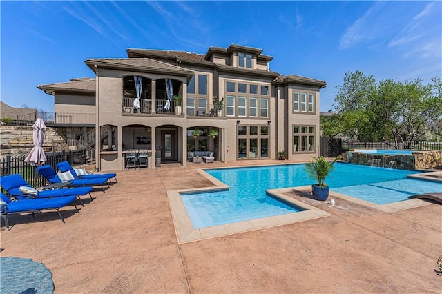 rear view of house featuring a balcony, a jacuzzi, a fenced in pool, a patio area, and fence private yard