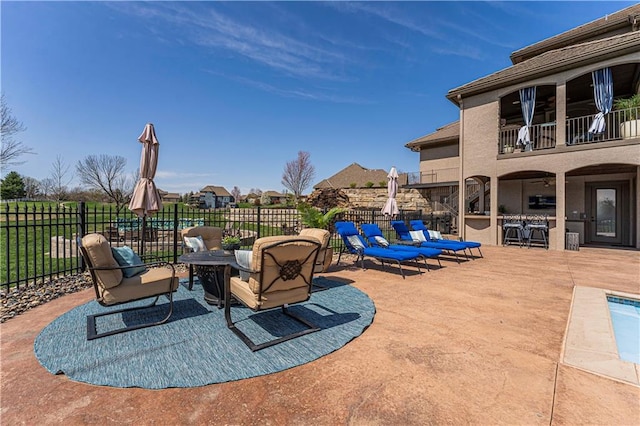 view of patio / terrace with fence, a fire pit, a ceiling fan, and a balcony
