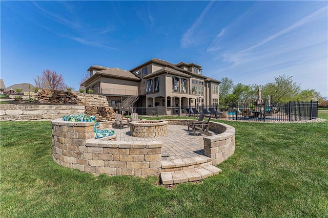 back of house featuring fence, a yard, a fire pit, and a patio area