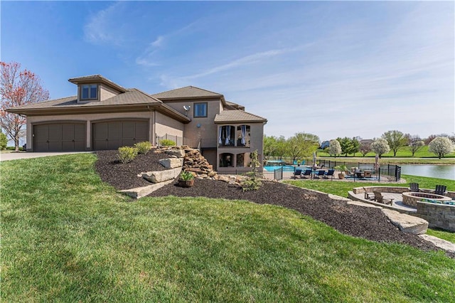 prairie-style house with a fire pit, a front yard, driveway, and an attached garage