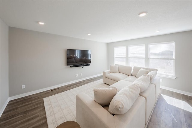 living area with baseboards, wood finished floors, and recessed lighting