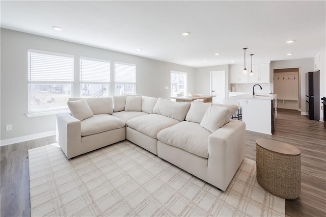 living room with recessed lighting, light wood-style flooring, and baseboards