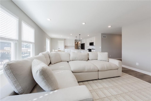 living area featuring recessed lighting, baseboards, visible vents, and light wood finished floors