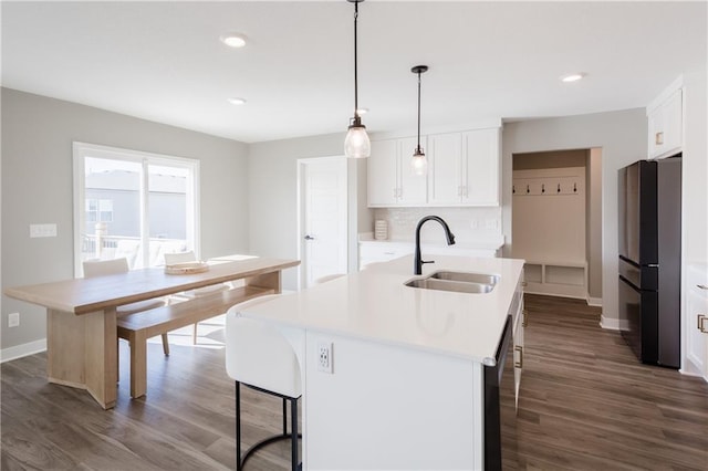 kitchen featuring dark wood finished floors, light countertops, freestanding refrigerator, a sink, and a kitchen bar