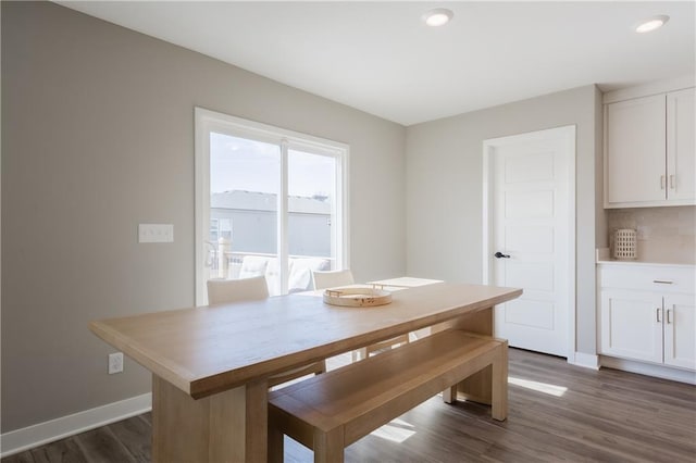 unfurnished dining area featuring dark wood-style flooring and baseboards