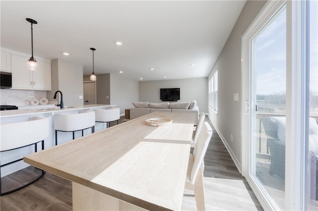 kitchen featuring white cabinets, decorative backsplash, light wood-style flooring, hanging light fixtures, and light countertops