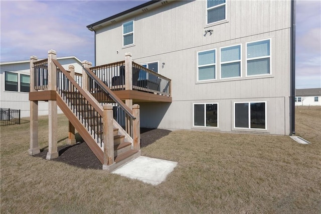 back of house featuring stairway, a deck, and a yard