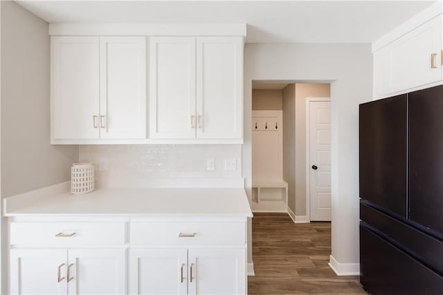 kitchen with light countertops, dark wood-style flooring, freestanding refrigerator, and white cabinetry