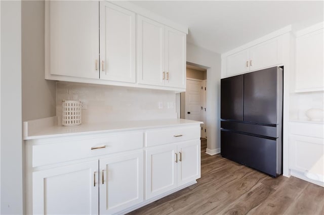 kitchen featuring light countertops, tasteful backsplash, freestanding refrigerator, and white cabinetry