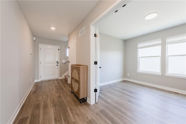 corridor featuring stairway, wood finished floors, visible vents, and baseboards