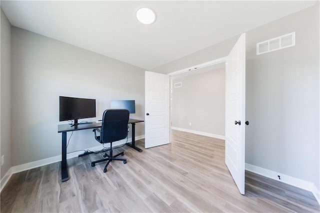 office area with wood finished floors, visible vents, and baseboards