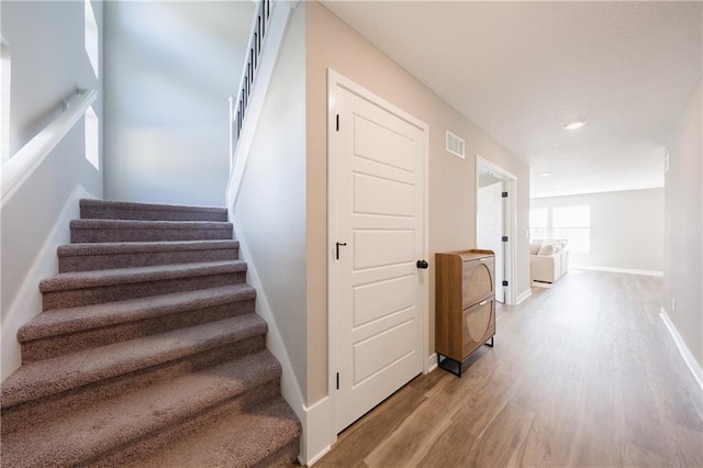 stairs featuring baseboards, visible vents, and wood finished floors