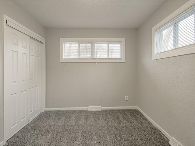 unfurnished bedroom with multiple windows, a closet, and carpet flooring