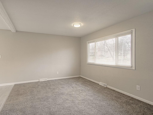 unfurnished room with baseboards, visible vents, carpet floors, and a textured ceiling