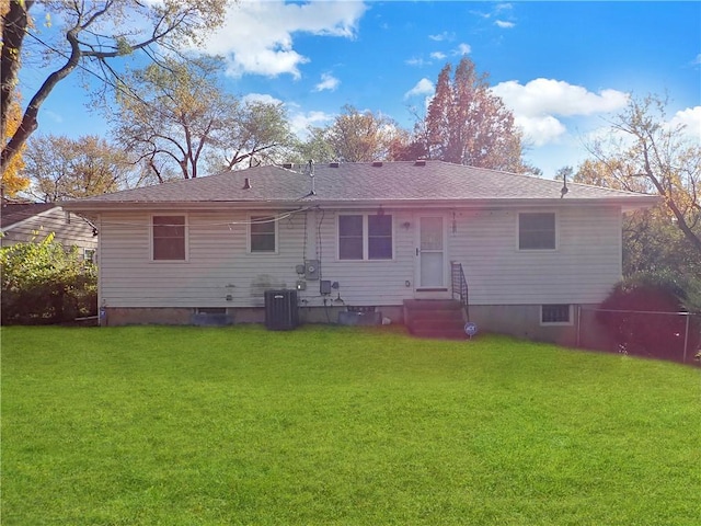 rear view of house with central AC and a lawn