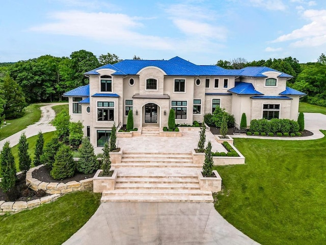 french country inspired facade featuring a front lawn and stucco siding