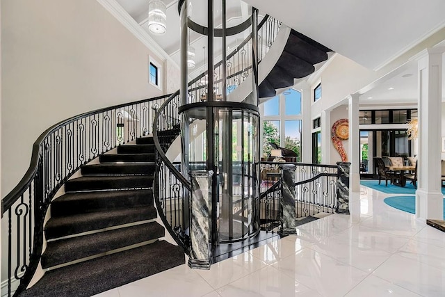 staircase with a healthy amount of sunlight, ornate columns, and crown molding