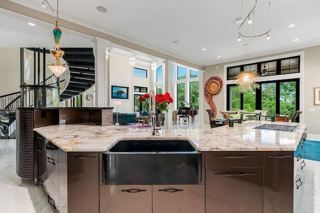 kitchen with modern cabinets, light stone counters, dark brown cabinets, and a wealth of natural light