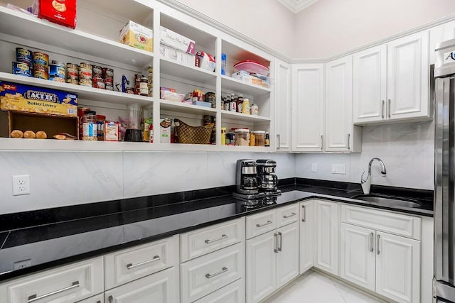 kitchen featuring dark countertops, white cabinetry, open shelves, and a sink