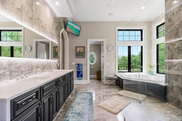 full bathroom featuring a sink, marble finish floor, backsplash, a bath, and double vanity