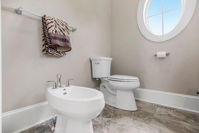 half bath with toilet, visible vents, a bidet, and baseboards