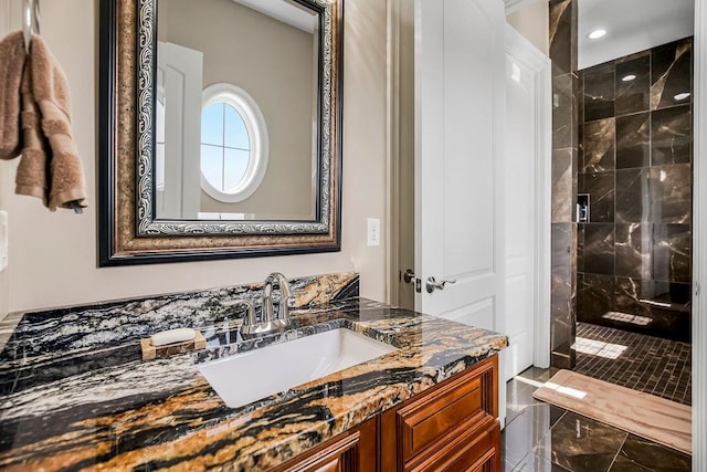 full bath with tiled shower and vanity