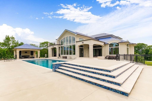 rear view of property with a patio area, fence, a fenced in pool, and stucco siding