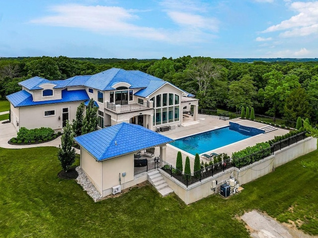 rear view of property with a patio, a balcony, fence, a yard, and stucco siding