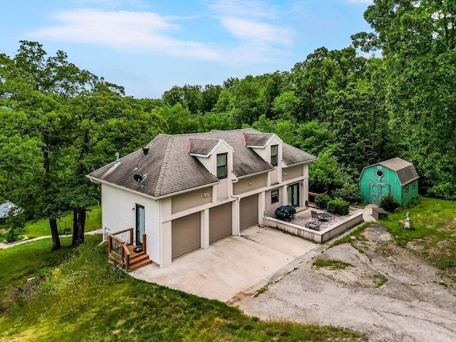 view of front of home with an outbuilding, a storage unit, a shingled roof, concrete driveway, and a garage