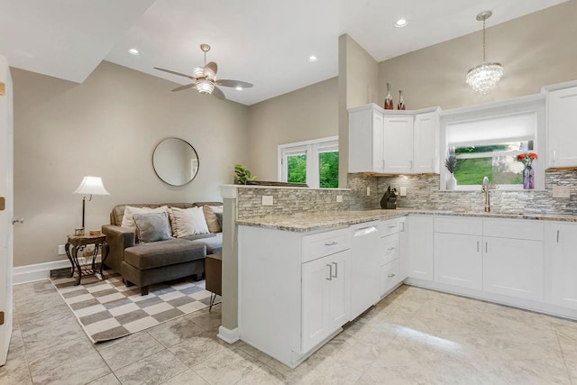 kitchen featuring light stone counters, open floor plan, white cabinetry, white dishwasher, and a peninsula