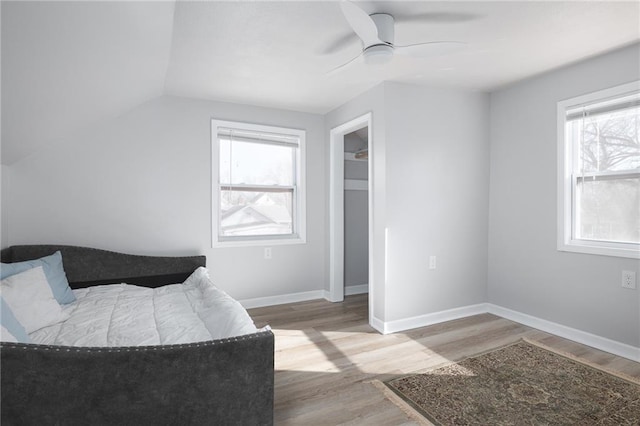 bedroom with multiple windows, wood-type flooring, and ceiling fan