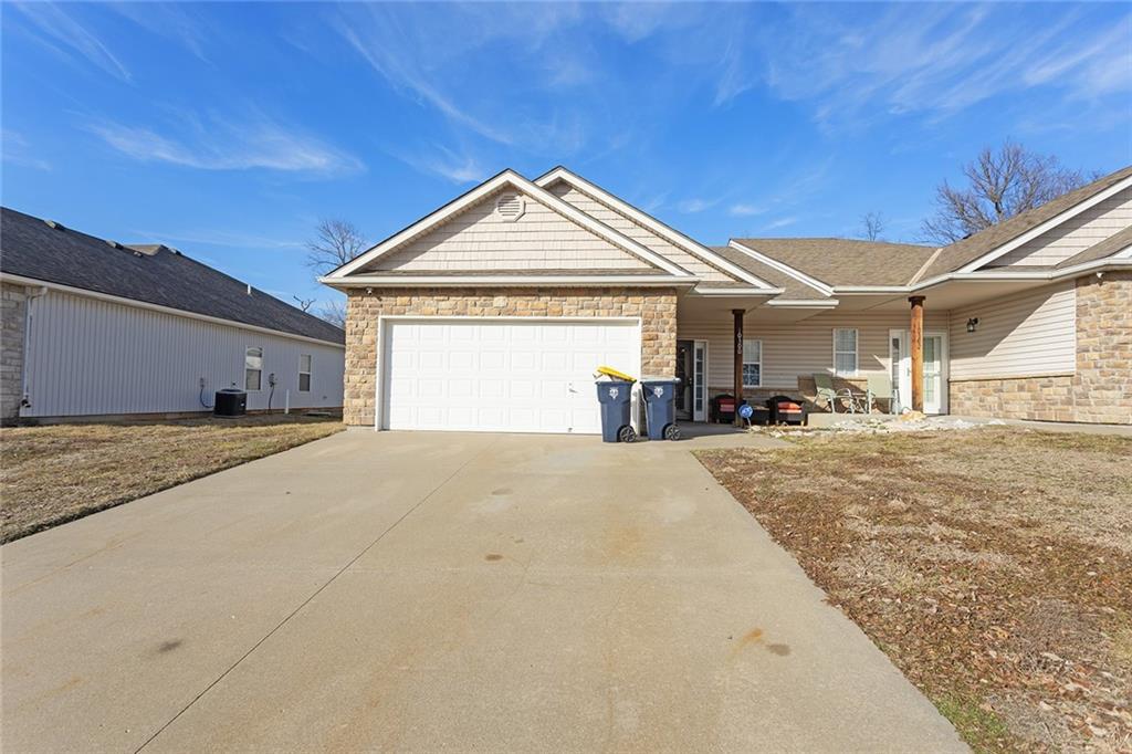 ranch-style home featuring central AC unit and a garage