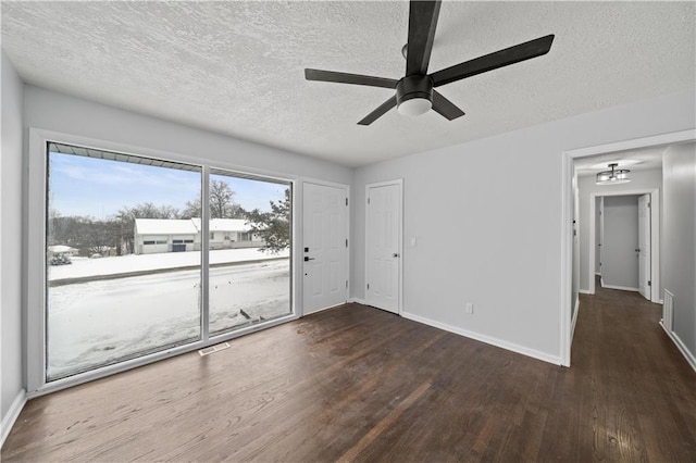 empty room with dark wood-type flooring, ceiling fan, and a textured ceiling