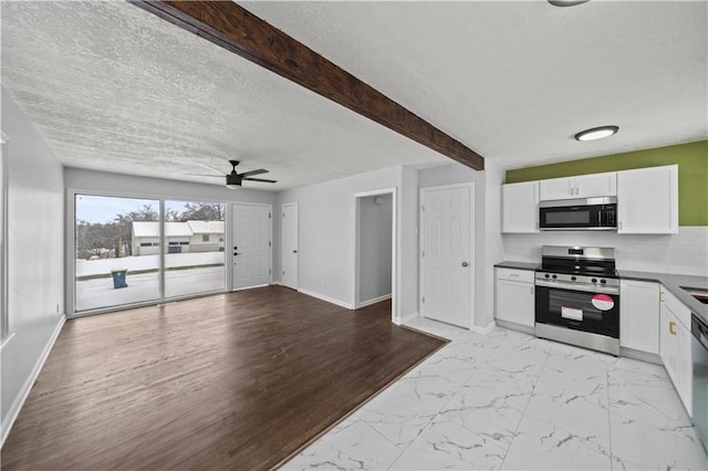 kitchen with beamed ceiling, stainless steel appliances, a textured ceiling, and white cabinets