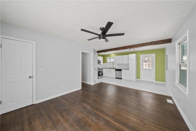 unfurnished living room featuring hardwood / wood-style floors, beamed ceiling, sink, ceiling fan, and a textured ceiling